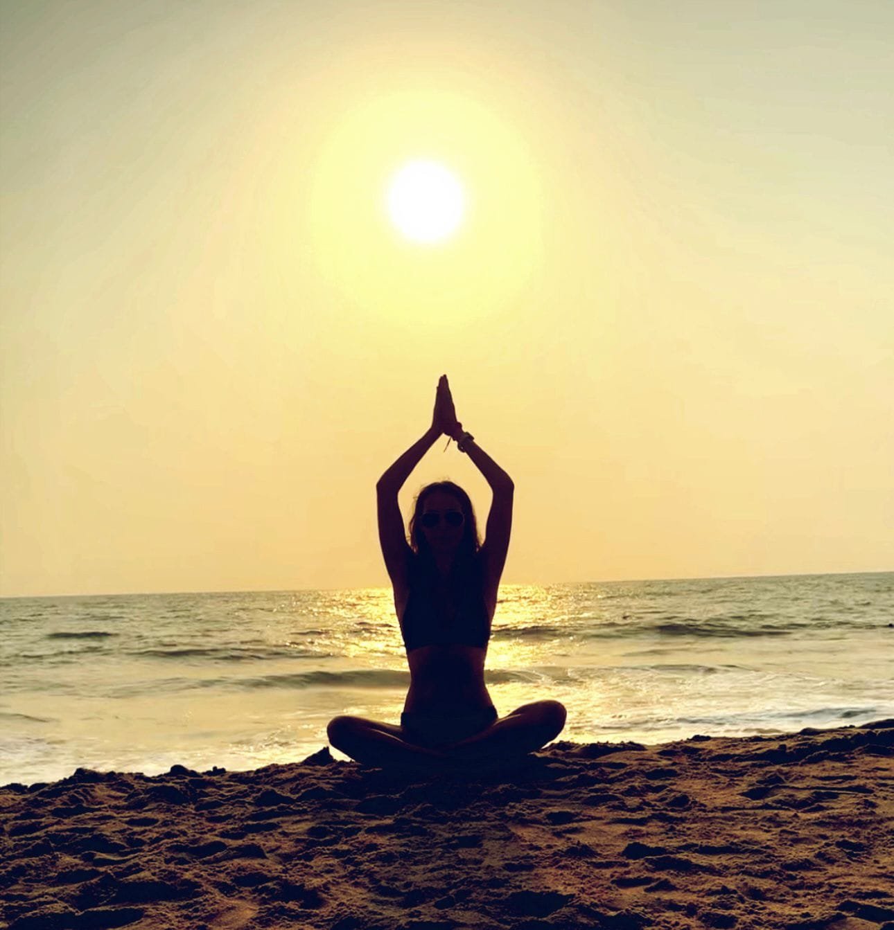 Silhouette of a person meditating on a beach at sunset